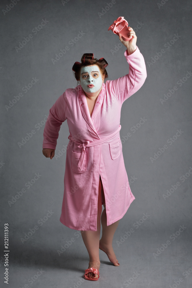 femme ronde et drôle avec bigoudis frappant avec une pantoufle Photos |  Adobe Stock