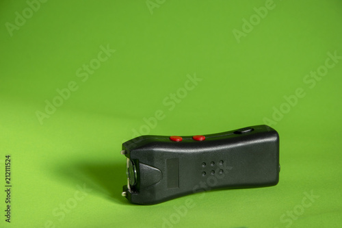 Electroshocker taser on a green background, safety and self-defense photo