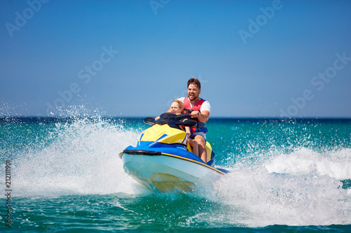 happy, excited family, father and son having fun on jet ski at summer vacation