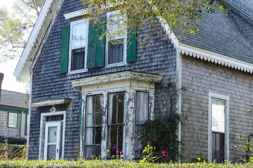 Weathered clapboard Cape Cod house with bay window and green shutters