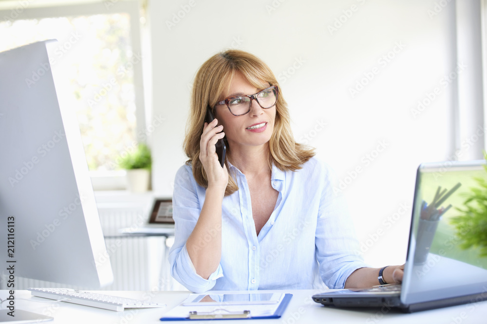 Successful businesswoman using her mobile phone at the office Successful businesswoman using her mobile phone at the office