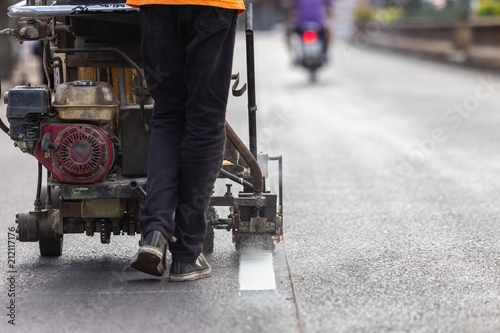 Man using machine to make traffic line stripe on the road