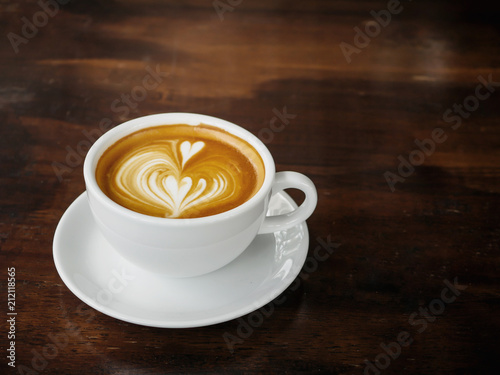 Cup of coffee with beautiful latte art on wooden table