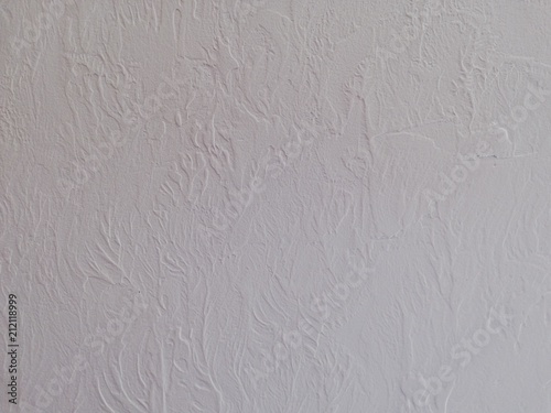 Texture of decorative plaster on the basis of small strokes on a stone wall and acrylic adhesive composition, close-up of an abstract background.