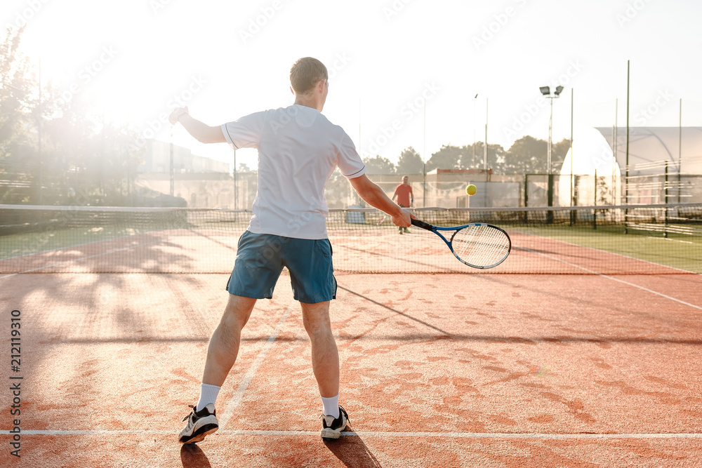  Man playing tennis in the morning in sunlight