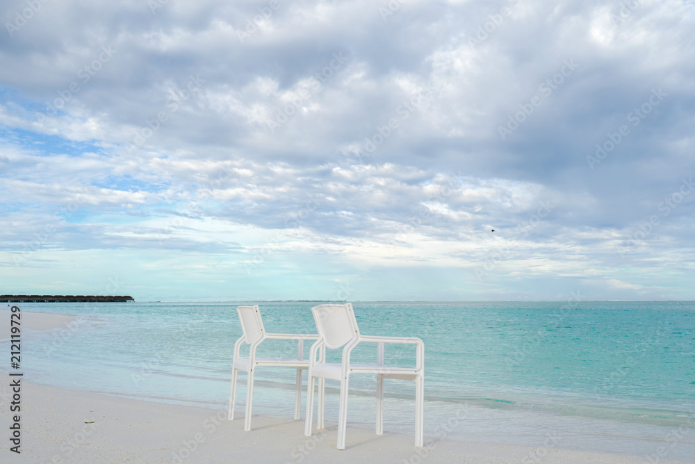 Summer concept , White chair on the beach white sand and turquoise sea color at maldives on the weekend holidays Summer concept , White chair on the beach white sand and turquoise sea color at maldives on the weekend holidays