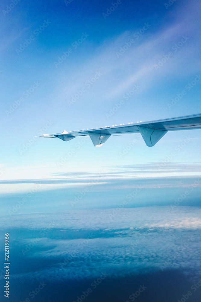 Naklejka premium Airplane wings in the sky and clouds, Classic image through aircraft window onto jet engine