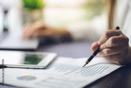 The accountant checking documents about graph and chart relating to financial reporting and tax accounting of the company. Picture is thin DOF selective focus at tip of fountain pen © godshutter