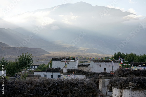 Tsarang village at sunset against the background of the Himalayas.  It is one of the later capitals of the Kingdom of Lo in the 14th century. Trekking to the closed zone of Upper Mustang. Nepal. photo