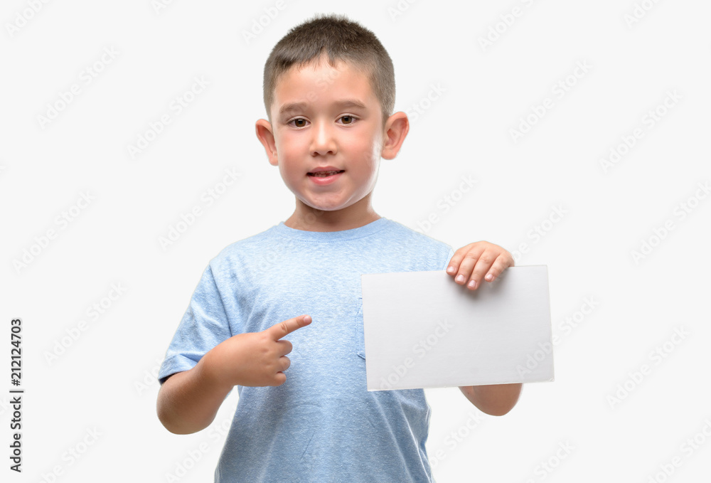 Dark haired little child holding a blank card very happy pointing with hand and finger Dark haired little child holding a blank card very happy pointing with hand and finger