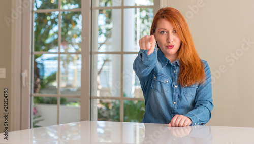 Redhead woman at home pointing with finger to the camera and to you, hand sign, positive and confident gesture from the front