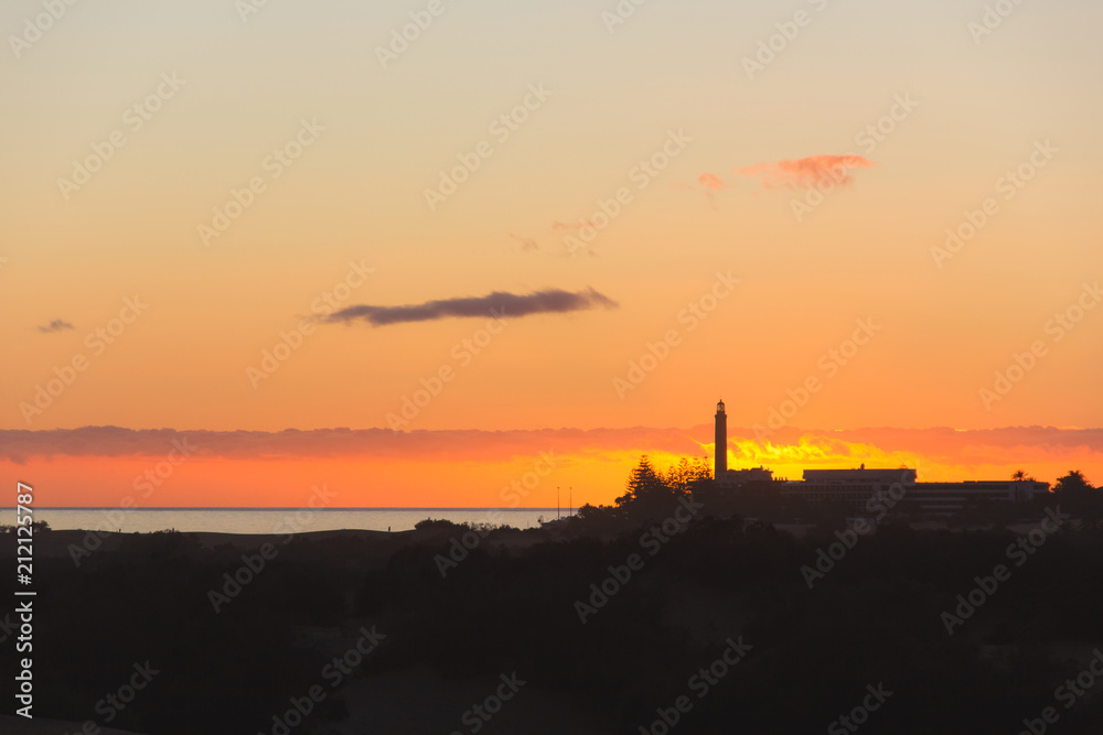 Maspalomas lighthouse silhouette with fire like sunset on the background in the island of Gran Canaria, Spain. Tourism destination concept