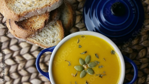 Morning fresh and healthy pumpkin soup in pot with bread in summer