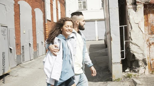 Slow motion, Young cheerful couple walking down the street, they go embracing, the girl smiles, they are happy
