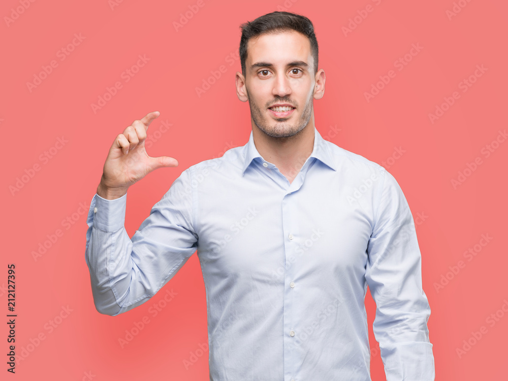 Handsome young businessman smiling and confident gesturing with hand doing size sign with fingers while looking and the camera. Measure concept.
