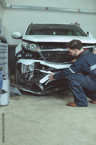 Mechanic examining damaged car