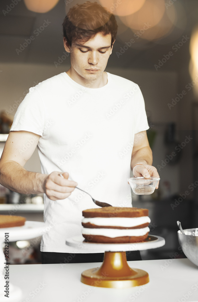 Young attractive man smearing sugar syrup on chocolate cake. Young attractive man smearing sugar syrup on chocolate cake.