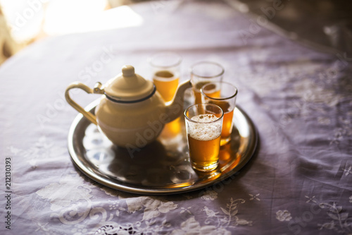 close up of a moroccan tea pot with glasses on a silver plate