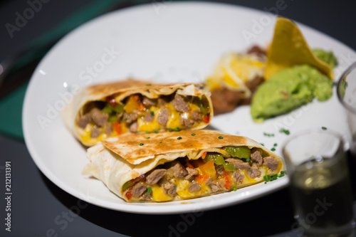 Tex-mex burrito with meat in sause on plate