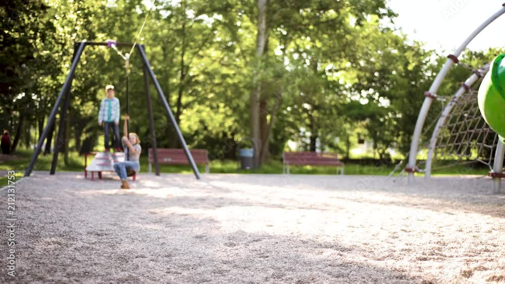 Children having fun is riding zipline. Cute girl and teen boy moving on zip line at playground - outdoors. Children having fun is riding zipline. Cute girl and teen boy moving on zip line at playground - outdoors.