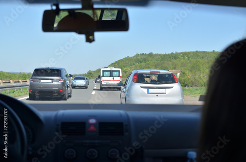 Driving on a highway with other vehicles and an ambulance car in front of him