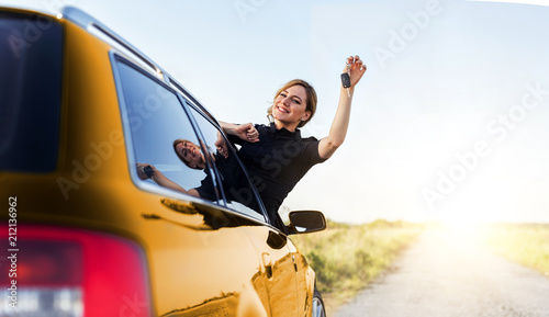 An attractive woman in the yellow car holds a car key in her hand. © Denis Rozhnovsky
