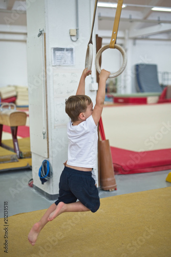 Little boy on gymnastic rings in professional gymnasium