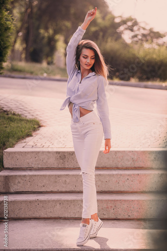 Beautiful young woman is happy raised her hand over head. She is smiling and looking at camera. photo