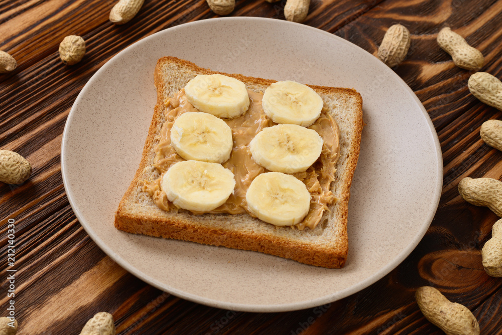 Peanut butter toast with banana slices on wooden background Peanut butter toast with banana slices on wooden background