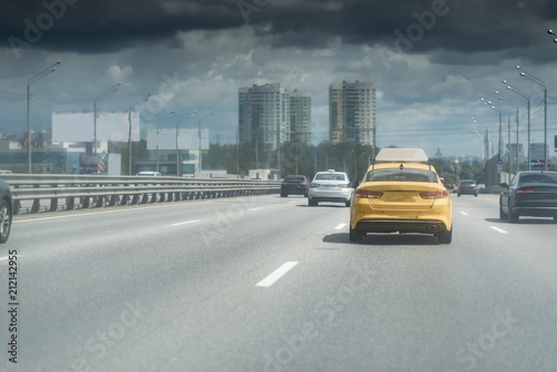 Yellow taxi car on the city highway under the dark clouds
