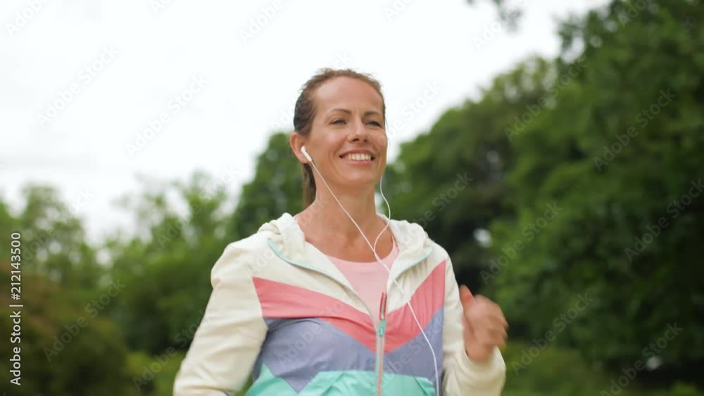 fitness, sport and healthy lifestyle concept - smiling woman with earphones running at park and listening to music fitness, sport and healthy lifestyle concept - smiling woman with earphones running at park and listening to music