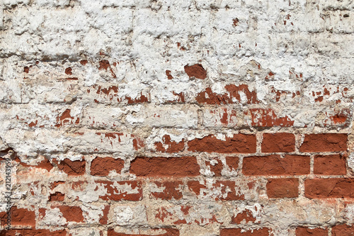vintage red brick wall on the building with white plaster peeling off from time © Masarik