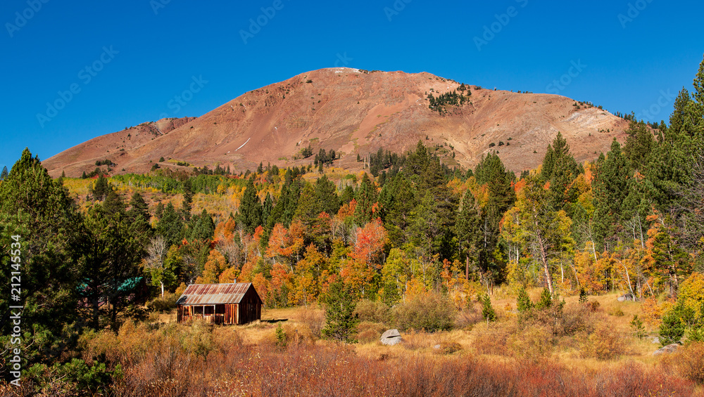 Cabin at foot of hill with autumn colored trees Cabin at foot of hill with autumn colored trees