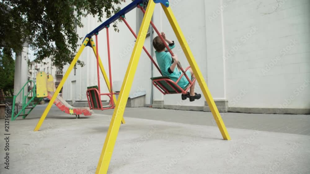 Happy carefree girl with two pigtails on a head seesaws at park Happy carefree girl with two pigtails on a head seesaws at park