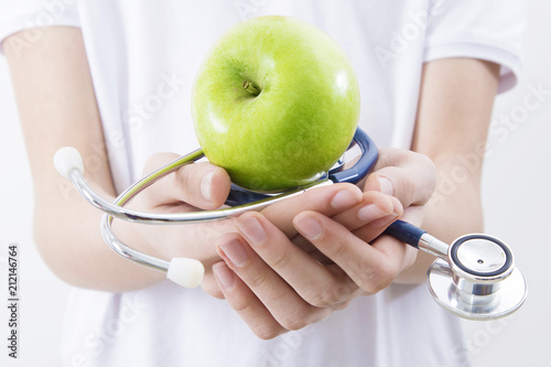 hands with stethoscope and green apple, healthy diet concept