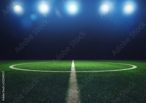 Midfield of grass soccer field at night with headlights