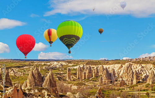 Hot air baloons flying over spectacular stone cliffs in Cappadocia
