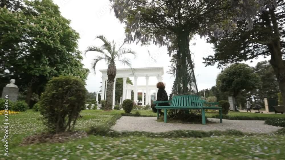 Woman relaxing in summer Batumi park, green trees and flowers in city garden Woman relaxing in summer Batumi park, green trees and flowers in city garden