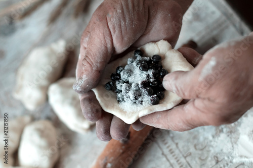 Dumplings with blueberries. Grandmother cooks on kitchen dumplings, pies, pierogi.