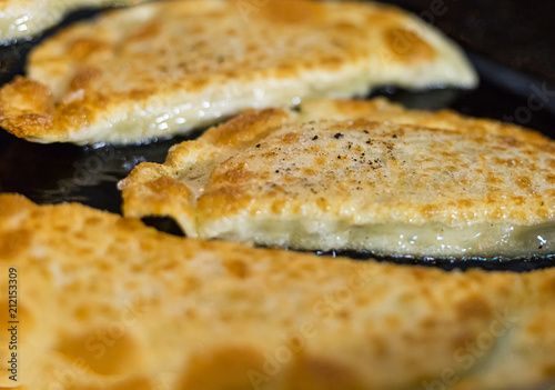 spicy juicy gedza dumplings with meat filling and Chinese cabbage fried in a frying pan golden crust close-up