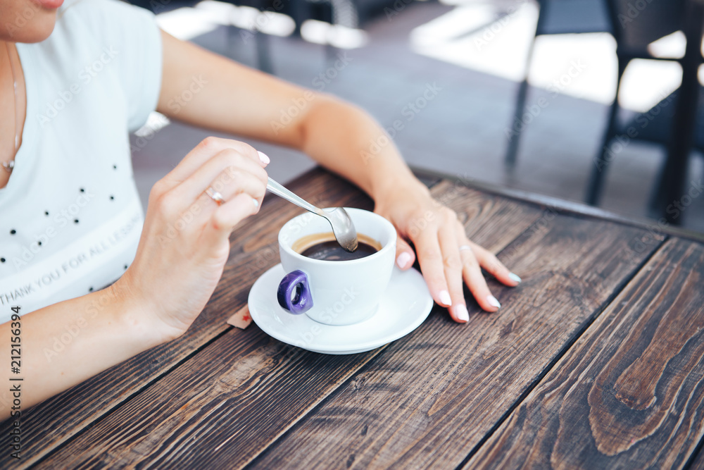 Woman holding a coffee spoon and hot coffee on a wooden table