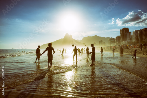 Distant sunset silhouettes playing keepy-uppie beach football on the sea shore in Ipanema Beach Rio de Janeiro Brazil photo