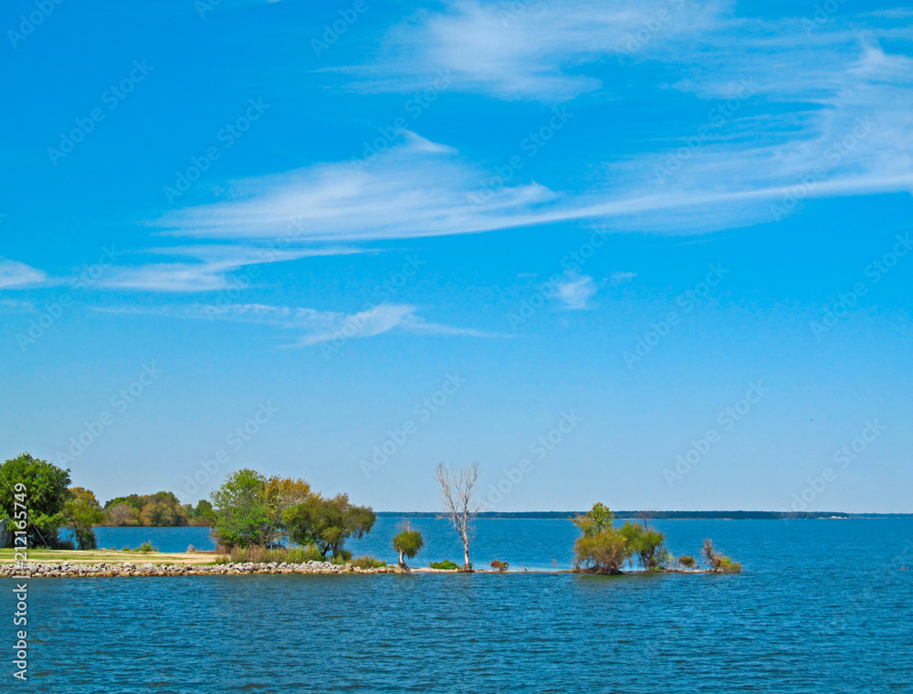 Landscape of a lake and blue sky. Bright view of Tawakoni Lake in Texas showing the surface of the water and the shore with green trees.