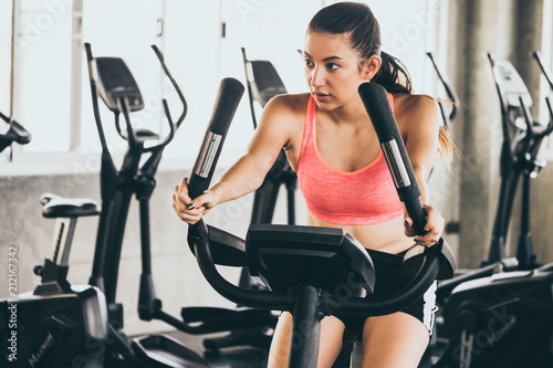 Attractive young woman working out on exercise bike at the gym.