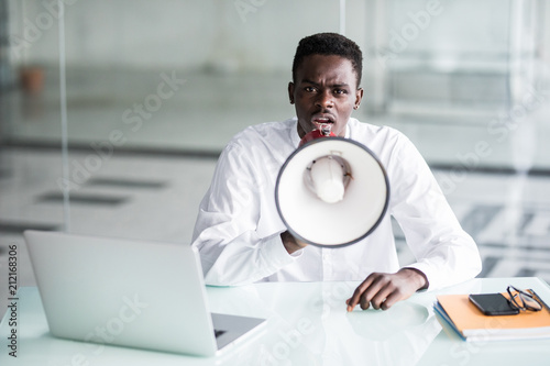 Afro businessman scream yelling through a megaphone in the office