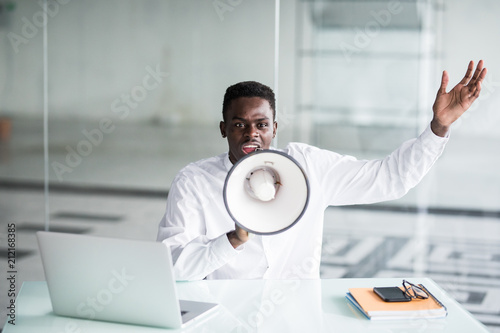 Obraz na plátne Afro businessman scream yelling through a megaphone in the office