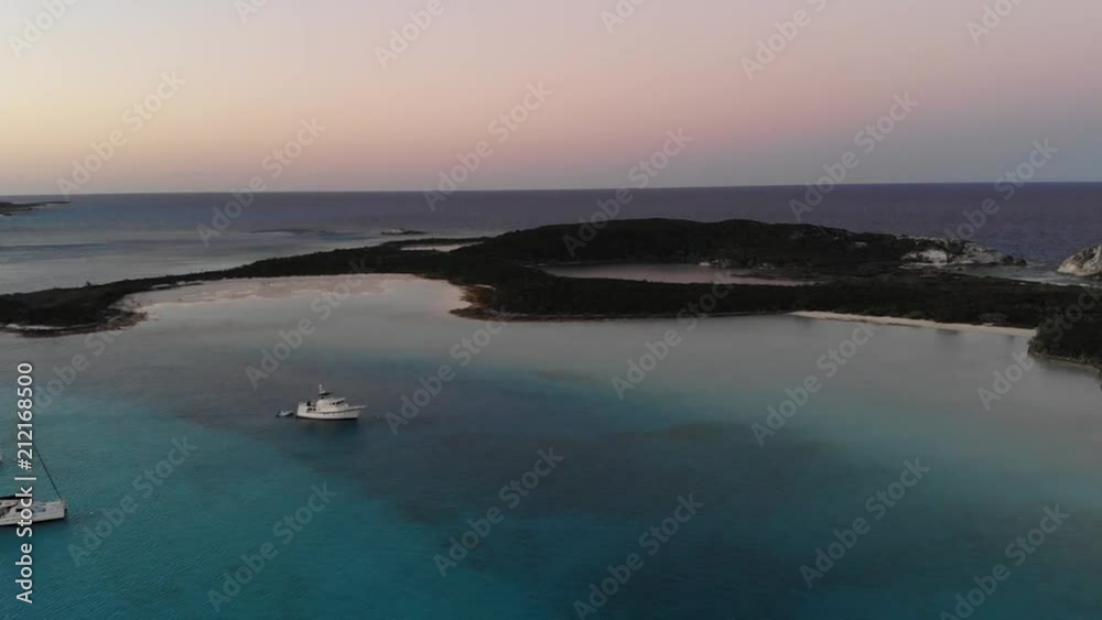 Beautiful glowing red, purple, and blue sunset over tiny islands in the Caribbean Sea. Multiple sailboats, tugboats, and sandy beaches in background. Beautiful glowing red, purple, and blue sunset over tiny islands in the Caribbean Sea. Multiple sailboats, tugboats, and sandy beaches in background.