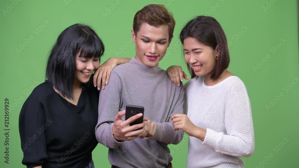 Three happy Asian friends using phone together Three happy Asian friends using phone together