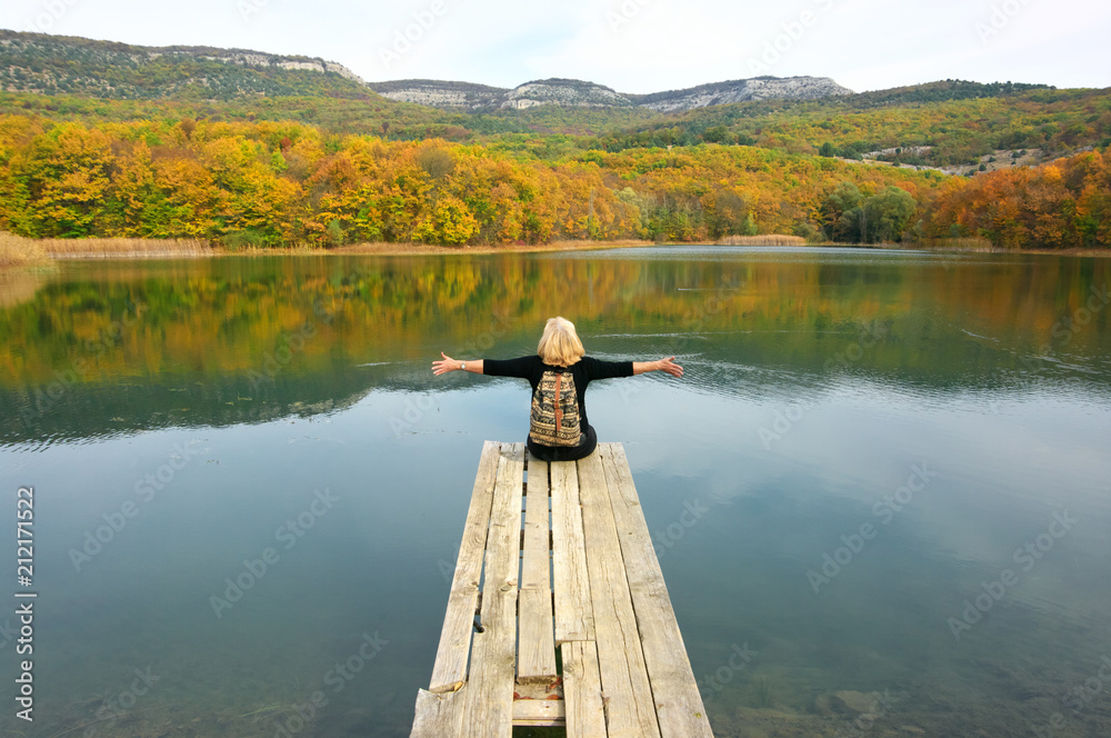 Hiker woman sitting over lake in autumnal day
