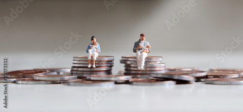 Canvas Print A miniature man and a miniature woman sitting with a baby on top of a stack of coins